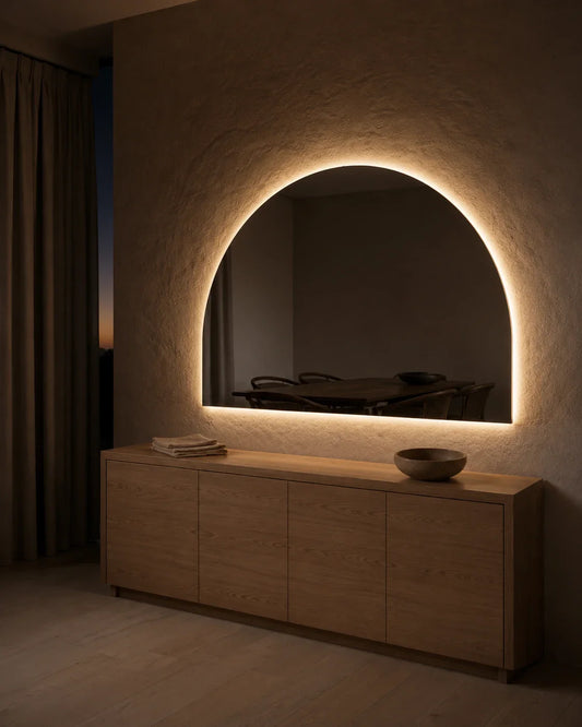 Danielle LED wall mirror glowing above a long sideboard in the evening