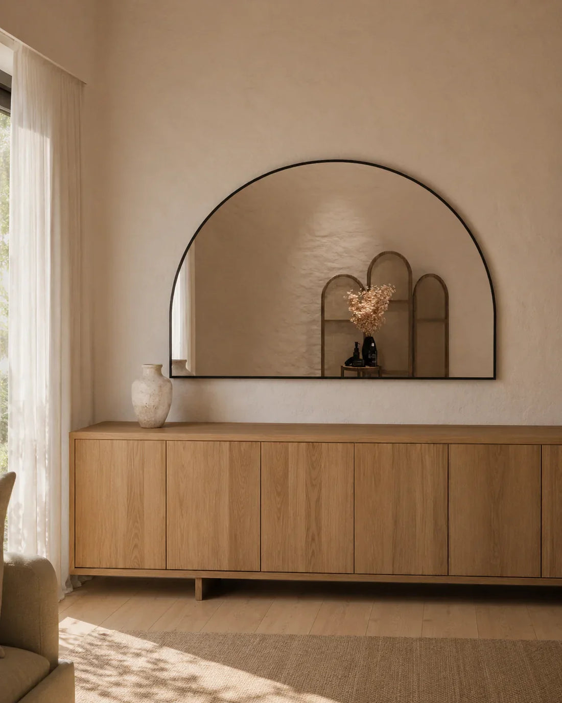 Danielle D-shape wall mirror styled above a long timber sideboard in a living room