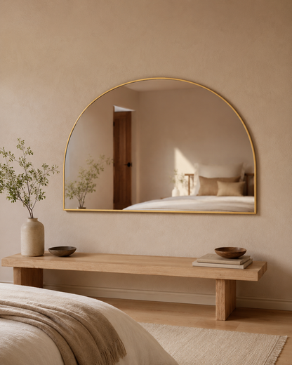 Danielle D-shape wall mirror in Brushed Gold, styled above a bench in a bedroom