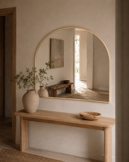 Vittoria arch wall mirror in Brushed Gold, styled above a console in a hallway