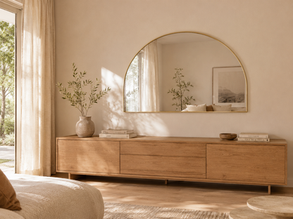 Danielle D-shape wall mirror in Brushed Gold, mounted above a timber sideboard in a warm living room
