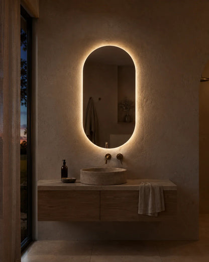 Elena LED wall mirror glowing above a bathroom vanity at dusk