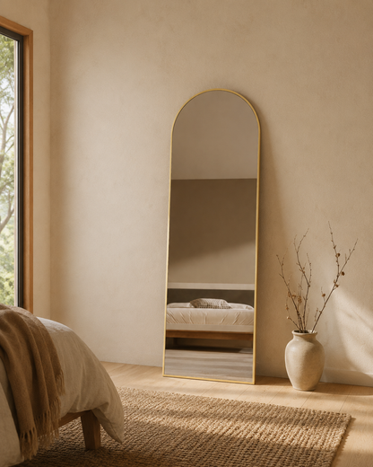 Sienna arch mirror 1700 x 610 in Brushed Gold, styled leaning in a bedroom corner