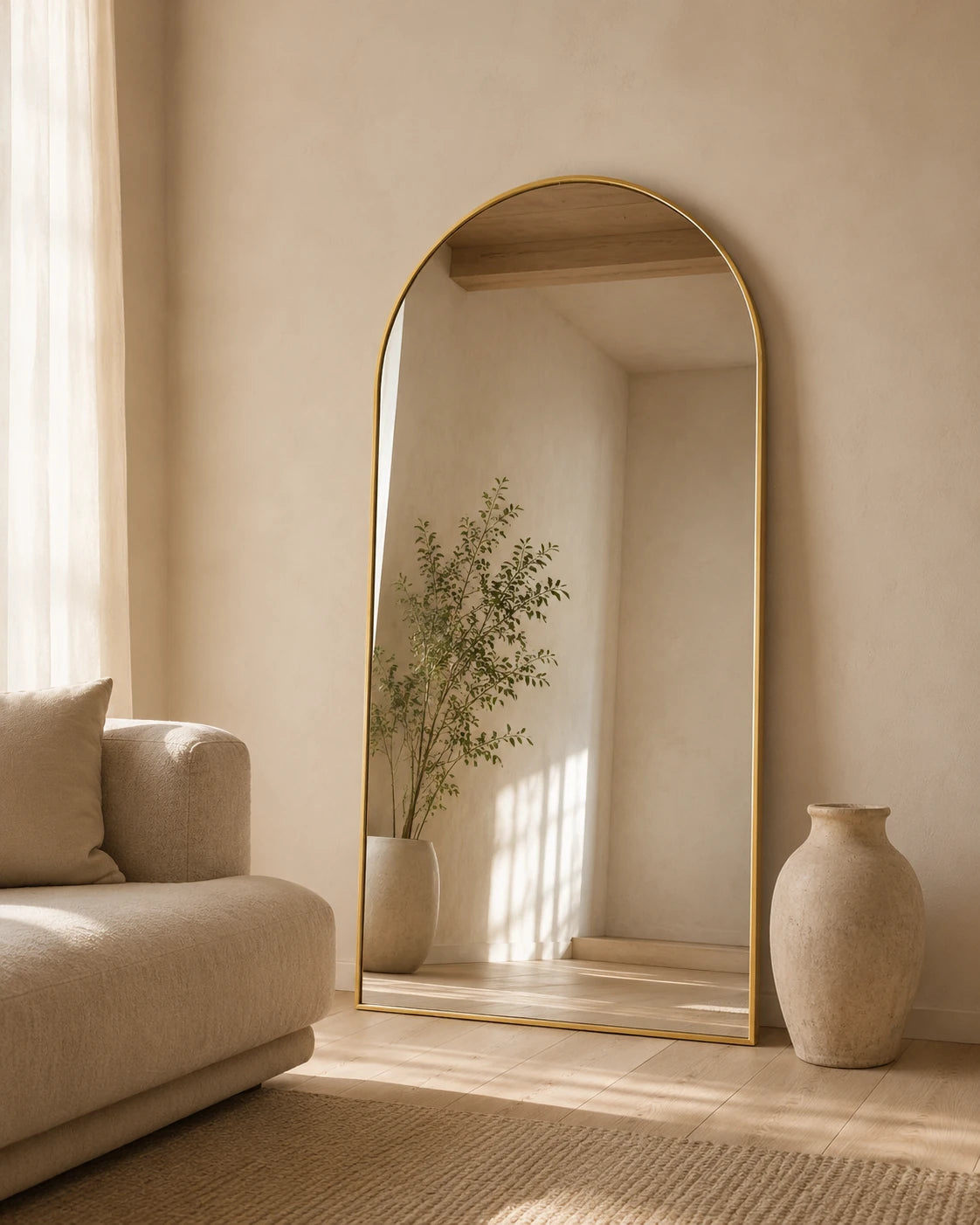 Sienna oversized arch mirror leaning behind a sofa beside tall vases