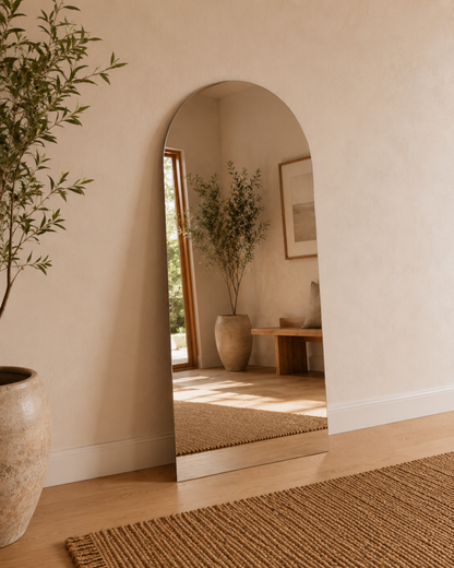 Vittoria frameless arch wall mirror leaning against a wall in a warm entryway
